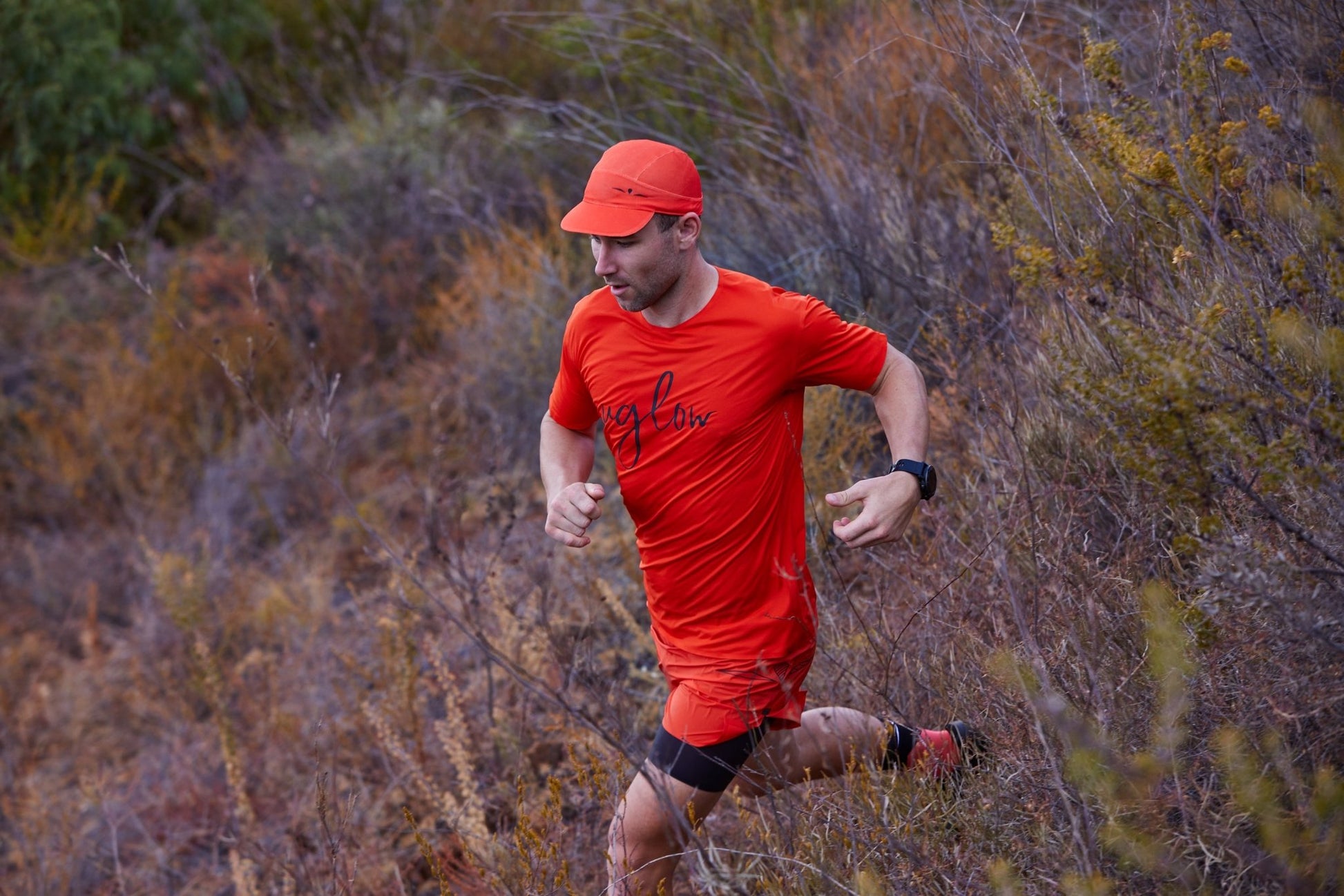 Løpende mann med mørk oransje caps med diskret svart Uglow symbol.